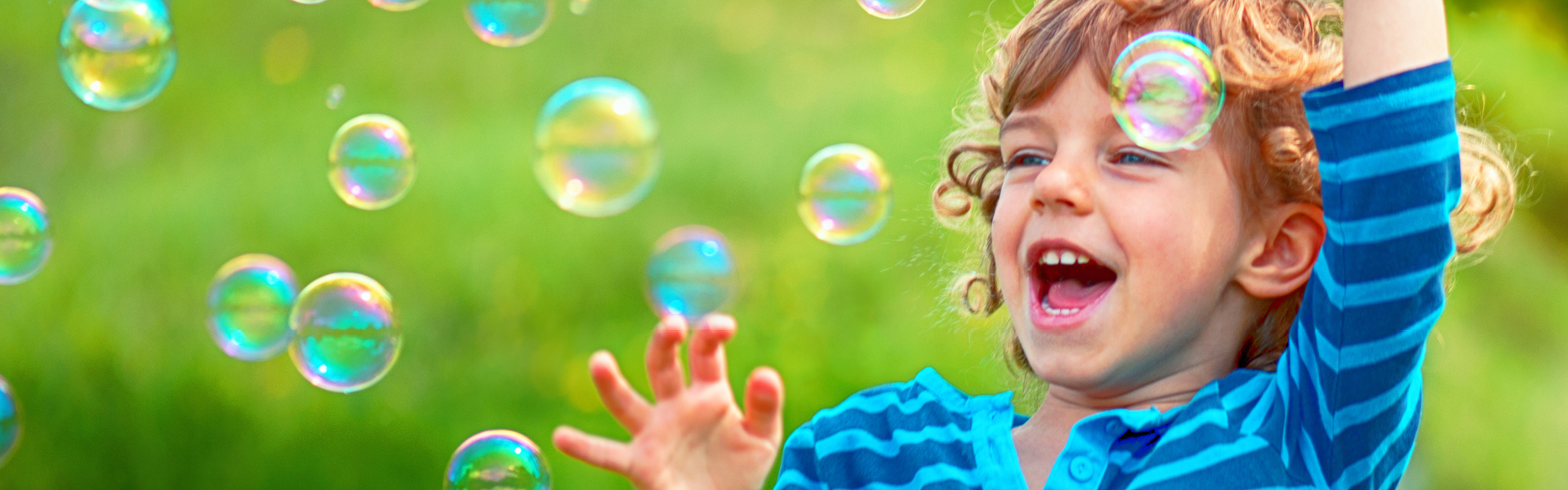Young child smiling playing with bubbles outside